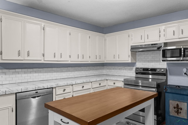 kitchen with wood counters, white cabinetry, a textured ceiling, appliances with stainless steel finishes, and decorative backsplash