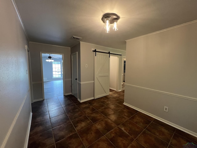 unfurnished room with a barn door, visible vents, baseboards, a ceiling fan, and ornamental molding