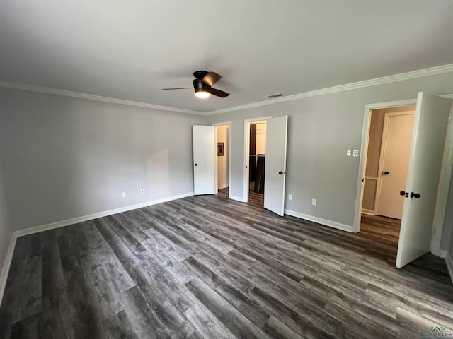 unfurnished bedroom with a ceiling fan, baseboards, a spacious closet, dark wood finished floors, and crown molding