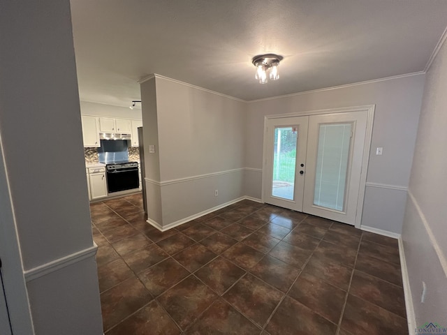 interior space with baseboards, french doors, dark tile patterned floors, and crown molding