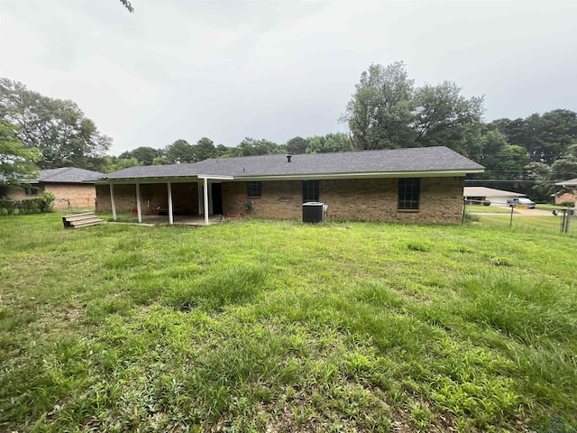 back of property with brick siding, a lawn, and fence