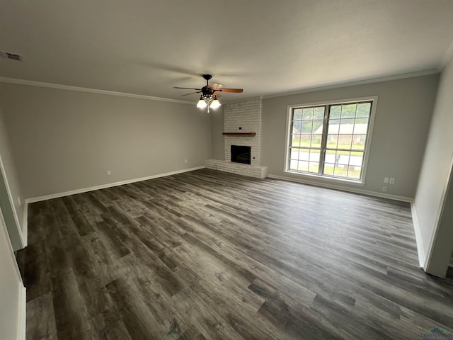 unfurnished living room with dark wood-type flooring, a fireplace, visible vents, baseboards, and ornamental molding