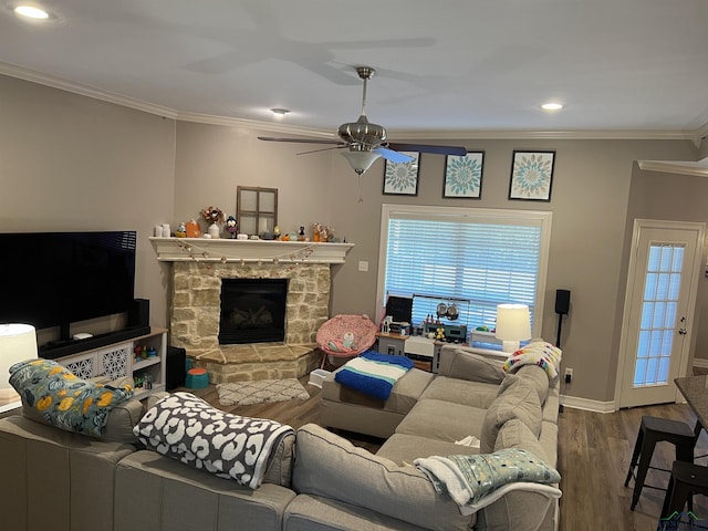 living room with hardwood / wood-style flooring, ceiling fan, a stone fireplace, and crown molding