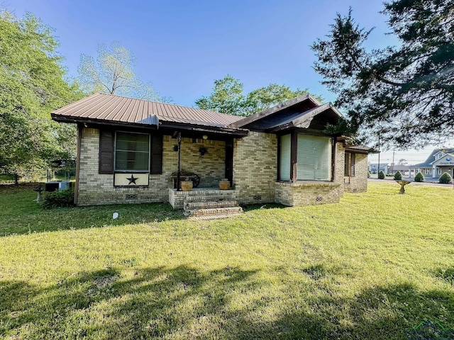 rear view of property featuring a lawn, brick siding, and metal roof