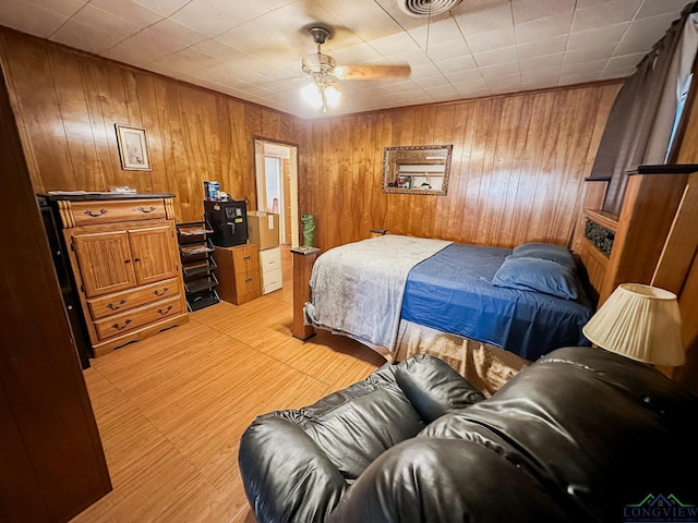 bedroom featuring wooden walls, light wood-style floors, and ceiling fan