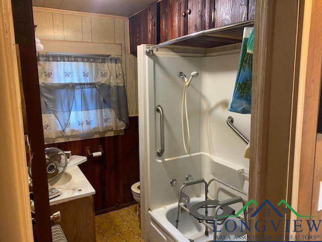 full bathroom featuring vanity, toilet, shower / bathtub combination, and wooden walls