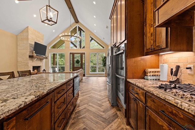 kitchen featuring dark parquet flooring, a stone fireplace, hanging light fixtures, light stone countertops, and beam ceiling