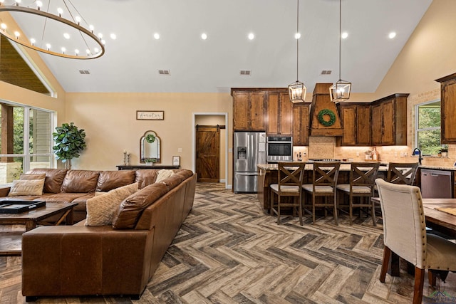 living room featuring a barn door and high vaulted ceiling