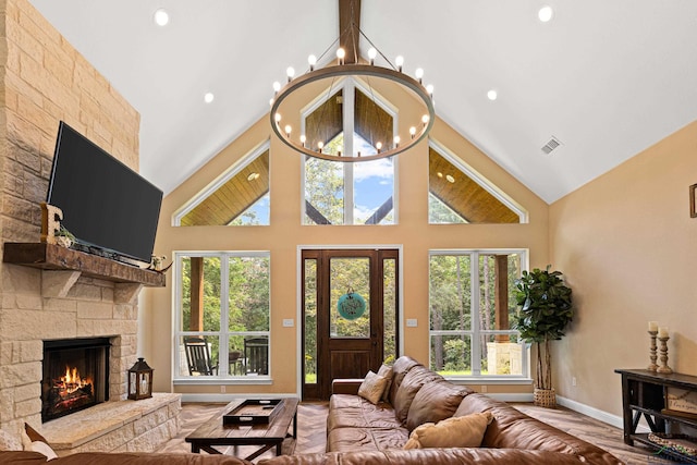 living room with a stone fireplace and high vaulted ceiling