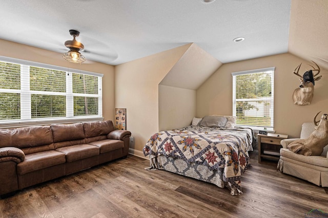 bedroom with hardwood / wood-style floors, a textured ceiling, vaulted ceiling, and ceiling fan