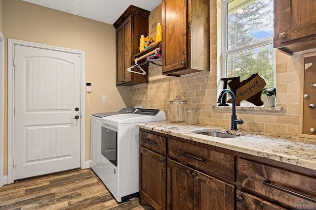 clothes washing area with cabinets, washing machine and dryer, dark hardwood / wood-style floors, and sink