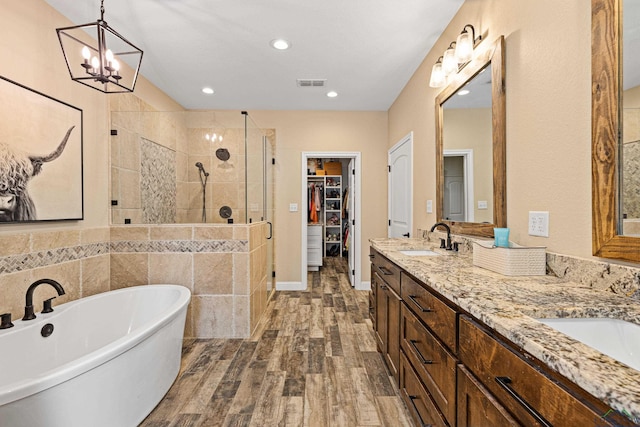 bathroom with hardwood / wood-style flooring, vanity, plus walk in shower, and a chandelier