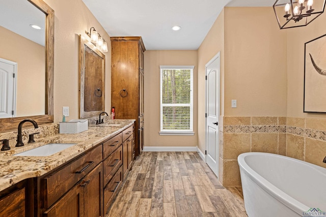 bathroom with a chandelier, a bathtub, vanity, and wood-type flooring