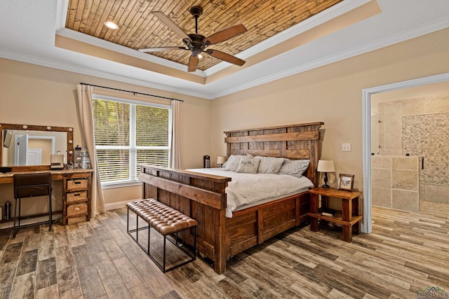 bedroom featuring ornamental molding, a tray ceiling, ceiling fan, wood-type flooring, and connected bathroom