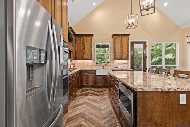 kitchen featuring pendant lighting, a kitchen island, stainless steel appliances, and high vaulted ceiling