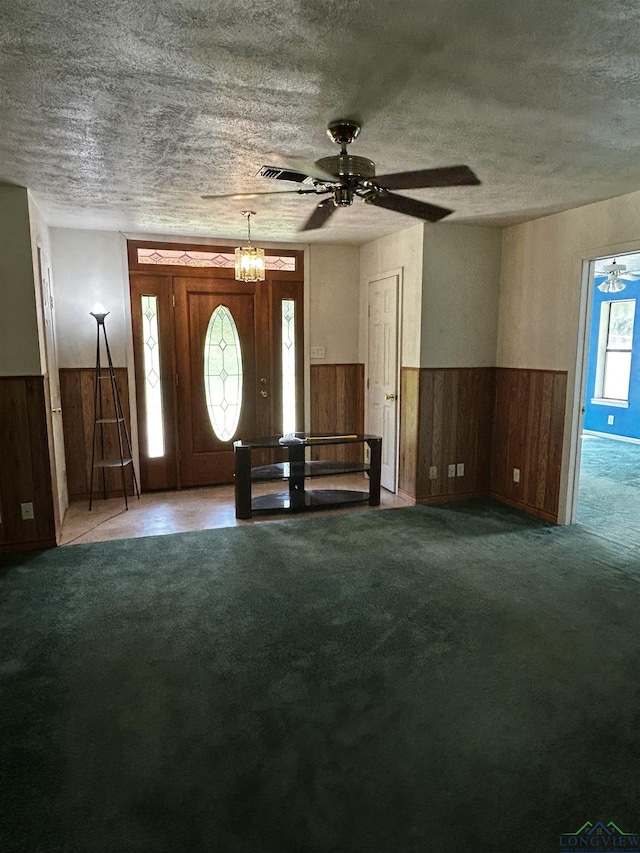 carpeted entrance foyer with a wainscoted wall, wooden walls, and a textured ceiling