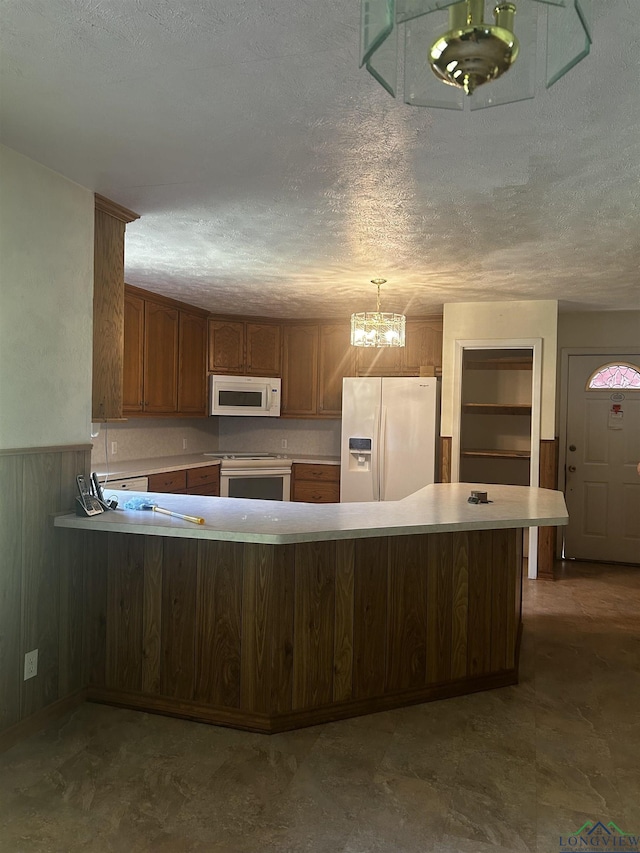 kitchen with white appliances, an inviting chandelier, wainscoting, light countertops, and a textured ceiling