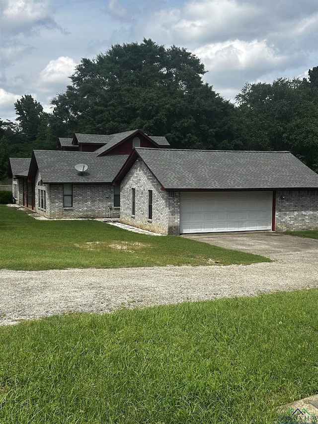 view of front of property featuring gravel driveway, brick siding, roof with shingles, a front yard, and an attached garage