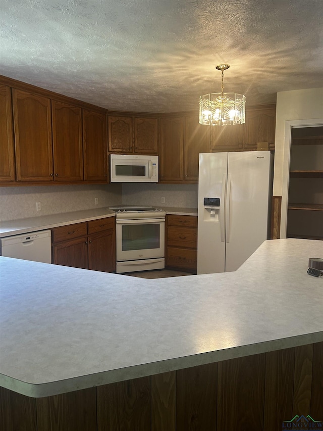 kitchen featuring white appliances, a textured ceiling, light countertops, and an inviting chandelier