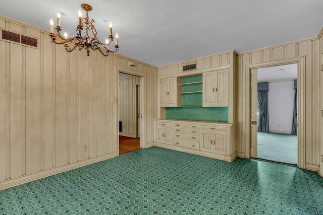 15 Covington Dr, Longview, TX 75602 - unfurnished dining area with a chandelier, carpet floors, wood walls, and crown molding