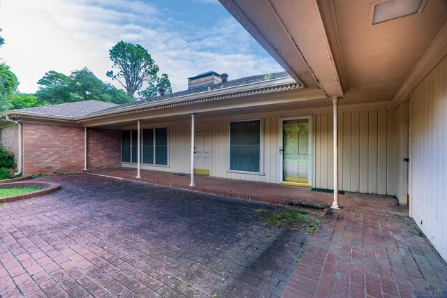 15 Covington Dr, Longview, TX 75602 - doorway to property with a chimney, brick siding, a patio, and a shingled roof
