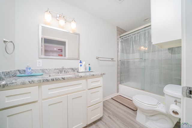 full bath with toilet, enclosed tub / shower combo, wood finished floors, and vanity