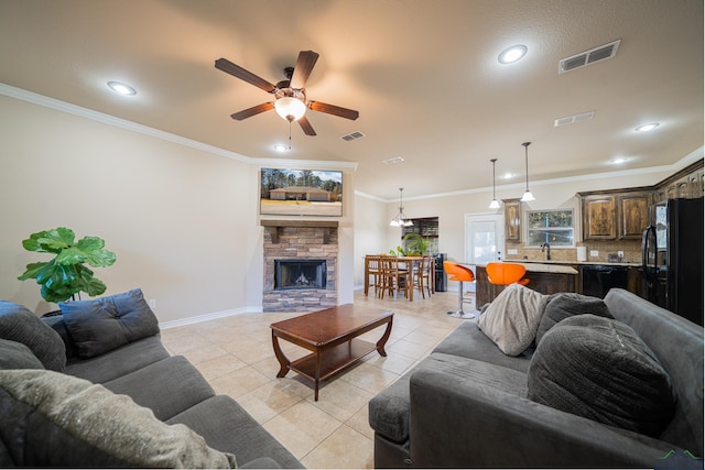 living area featuring visible vents, crown molding, a stone fireplace, and light tile patterned flooring