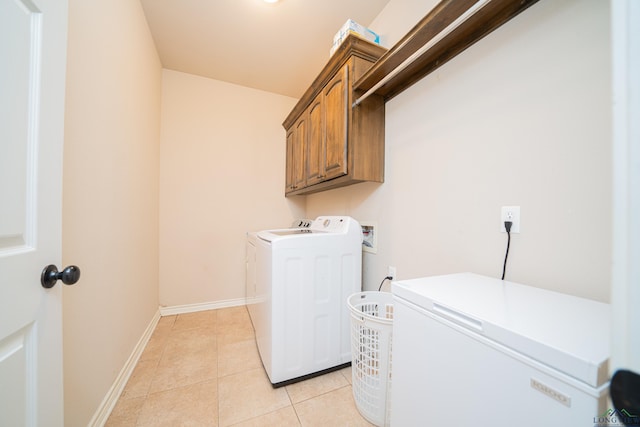 clothes washing area with cabinet space, light tile patterned floors, baseboards, and independent washer and dryer