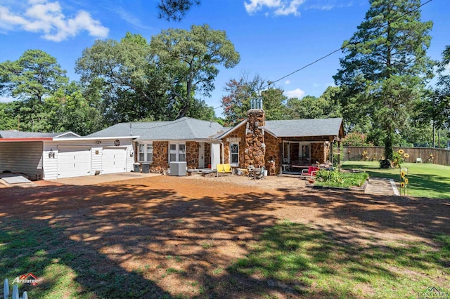 single story home with covered porch, a garage, and central AC unit