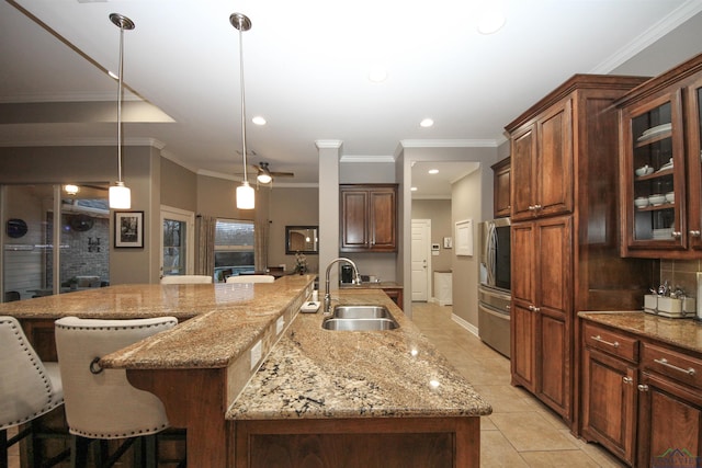 kitchen featuring pendant lighting, sink, light tile patterned floors, a breakfast bar area, and a large island with sink