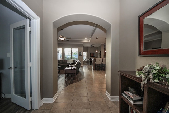 hallway with a tray ceiling and tile patterned floors