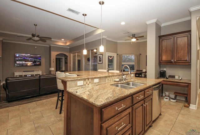 kitchen with sink, light stone counters, stainless steel dishwasher, an island with sink, and pendant lighting