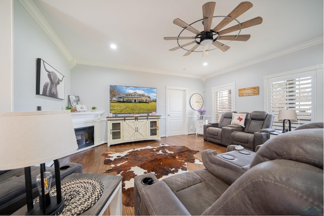 living room with crown molding, recessed lighting, a glass covered fireplace, ceiling fan, and wood finished floors