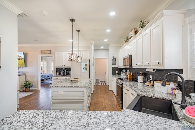 kitchen featuring stainless steel appliances, wood finished floors, a sink, ornamental molding, and tasteful backsplash