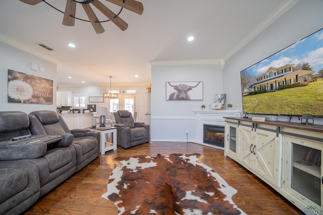 living area featuring a fireplace, visible vents, dark wood-style flooring, and crown molding