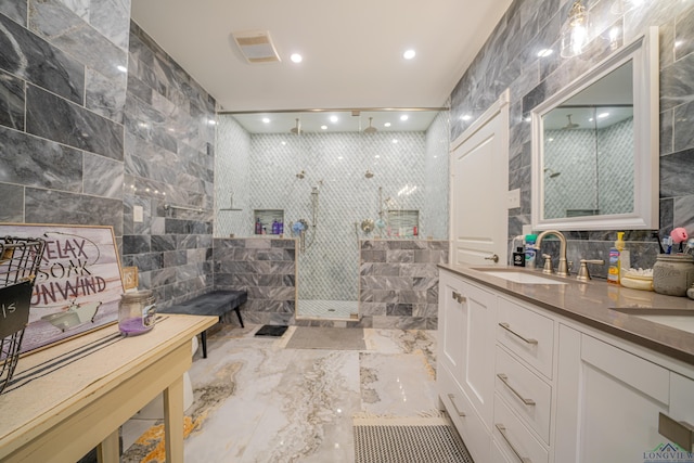 full bath with marble finish floor, vanity, a walk in shower, tile walls, and recessed lighting