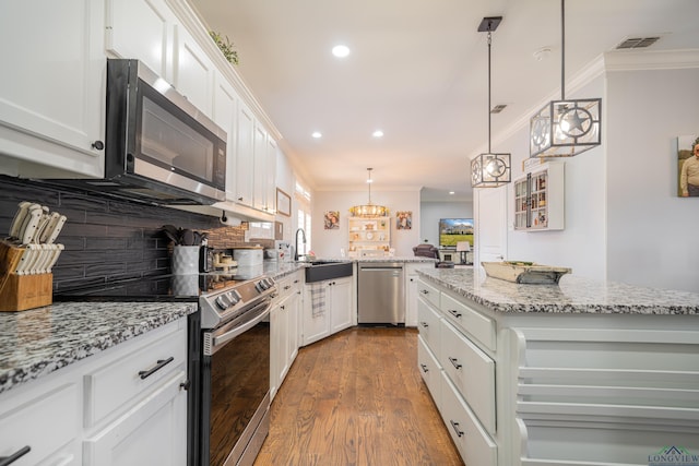 kitchen with crown molding, visible vents, backsplash, appliances with stainless steel finishes, and a sink