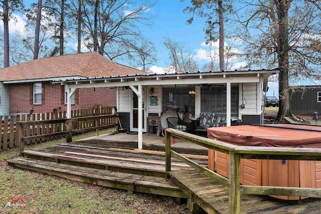 rear view of property with a hot tub and a deck