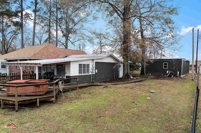 back of house featuring a shed, a lawn, a hot tub, and a deck