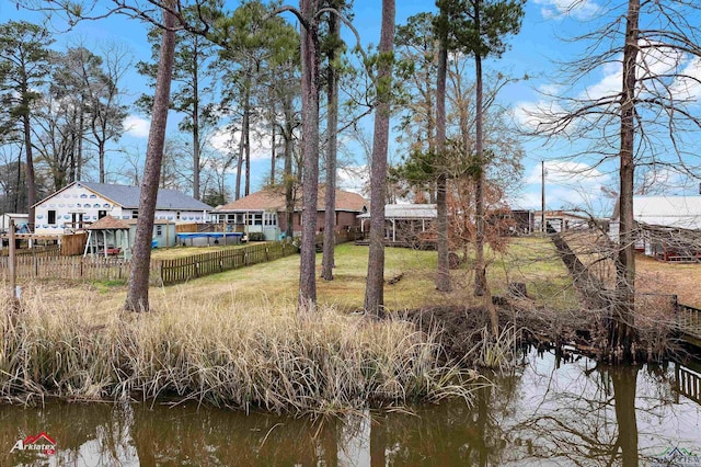 back of house with a water view and a lawn