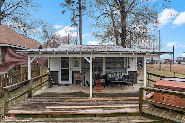 rear view of house featuring a hot tub and a deck