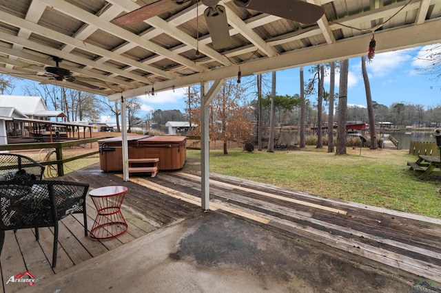 wooden terrace with ceiling fan, a hot tub, and a lawn