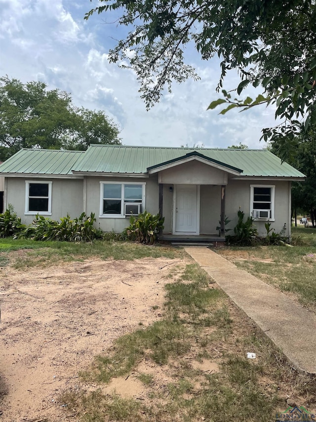 single story home with metal roof, cooling unit, and a front yard