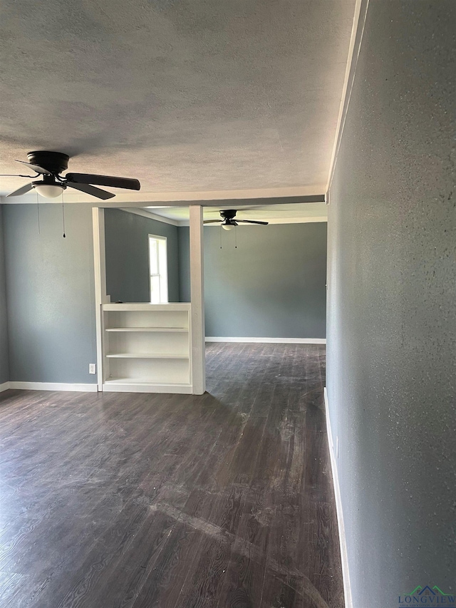 interior space with ceiling fan, a textured ceiling, baseboards, and dark wood-style flooring