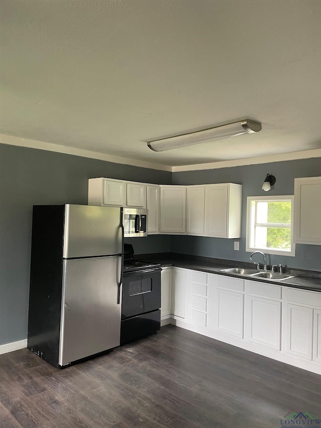 kitchen with stainless steel appliances, dark countertops, a sink, and white cabinets