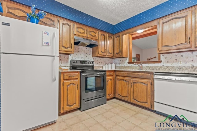 kitchen with a textured ceiling, white appliances, and sink