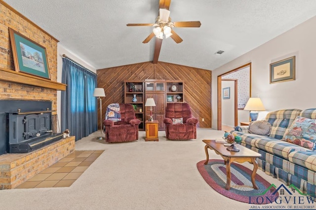 carpeted living room featuring wood walls, a wood stove, lofted ceiling with beams, ceiling fan, and a textured ceiling