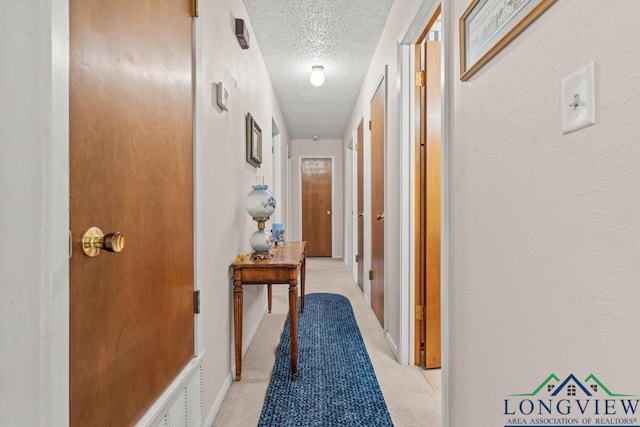 corridor with a textured ceiling and light carpet