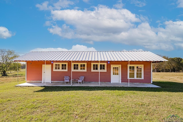back of property with a patio area, a yard, and metal roof