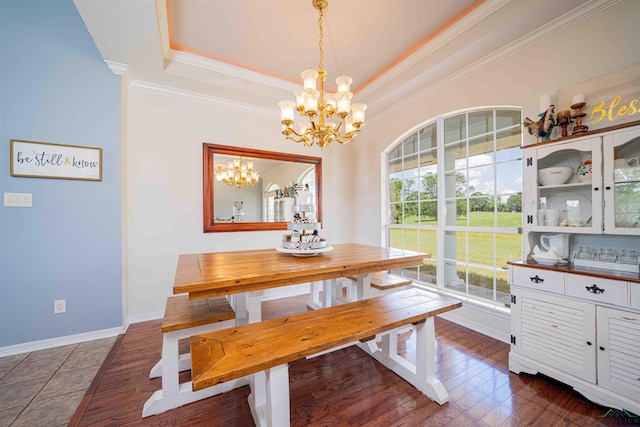 dining area featuring an inviting chandelier, baseboards, crown molding, and a tray ceiling